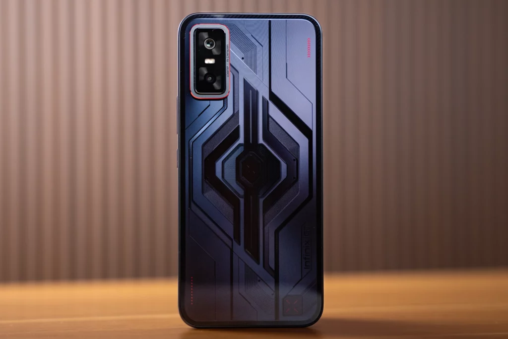 A product shot of the Infinix GT 30 Pro smartphone in a black and purple color. The back of the phone features a prominent geometric design and a vertical rectangular camera module with a red outline.