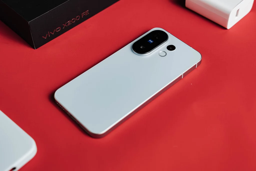 White smartphone with accessories and "vivo X200 FE" box on red.