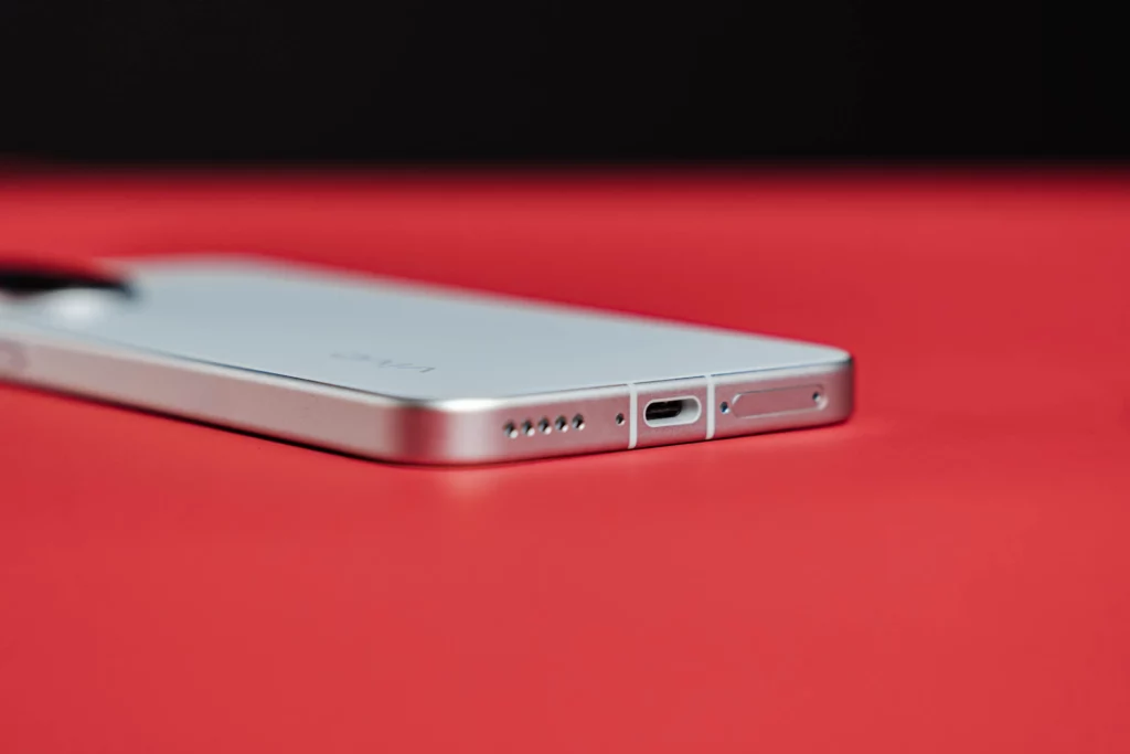 Bottom view of a white smartphone showing charging port and speaker grilles.