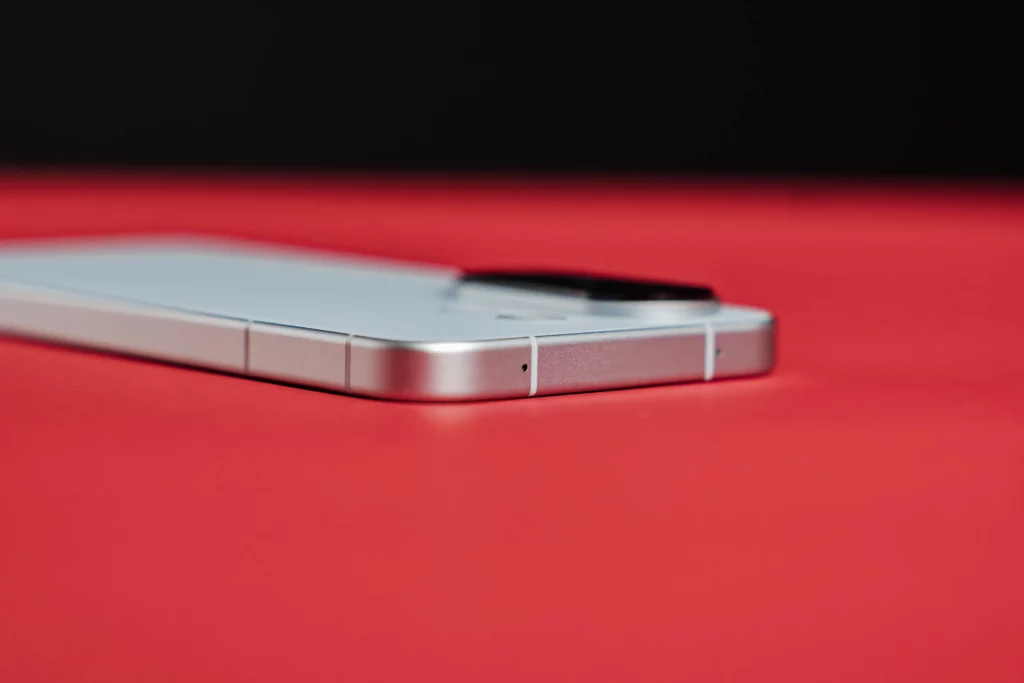 Close-up side view of a white smartphone on a red surface.
