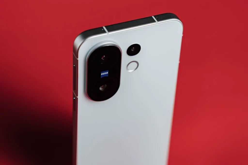 Angled close-up of the back of a white smartphone with "ZEISS" logo on the camera.