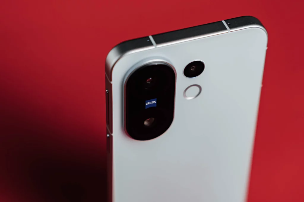 Angled view of the white smartphone's camera module on a red surface.