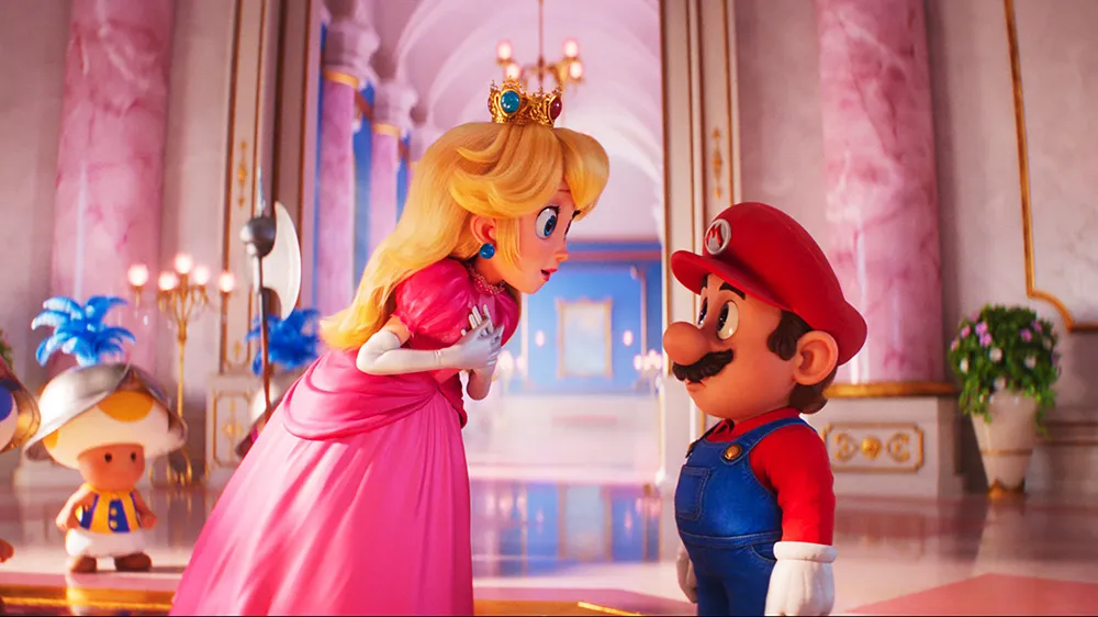 Princess Peach, in a flowing pink gown and crown, leans down to speak with Mario, who is looking up at her in his signature red cap and blue overalls. They are inside a grand, brightly lit hall with marble columns and chandeliers. A small Toad character is partially visible on the left.