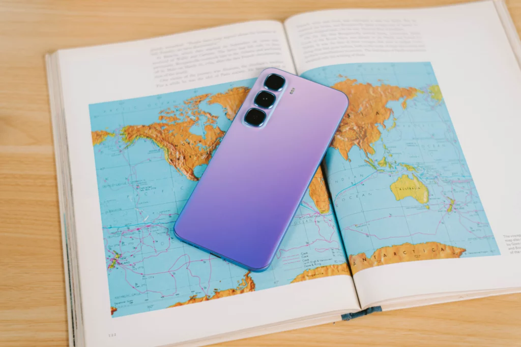 The Infinix HOT 60 Pro+ smartphone resting on an open book showing a detailed world map.