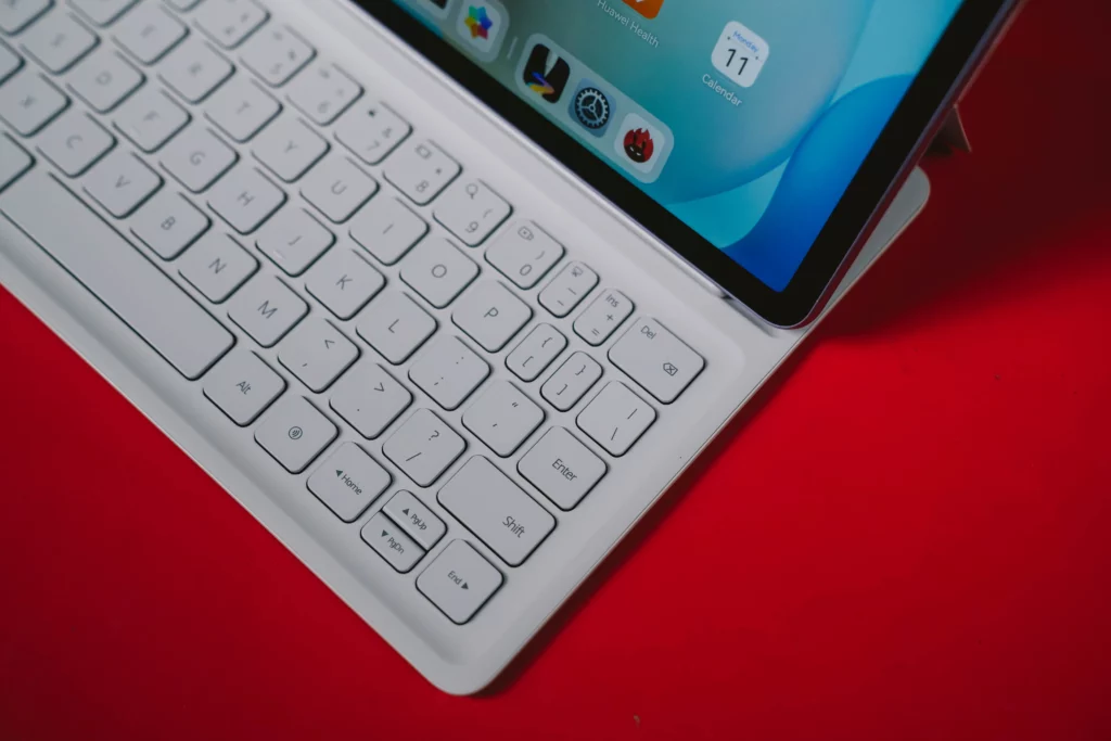 A close-up of the white HUAWEI Smart Keyboard, showing the keys and a portion of the tablet's screen displaying the home screen with a calendar icon.