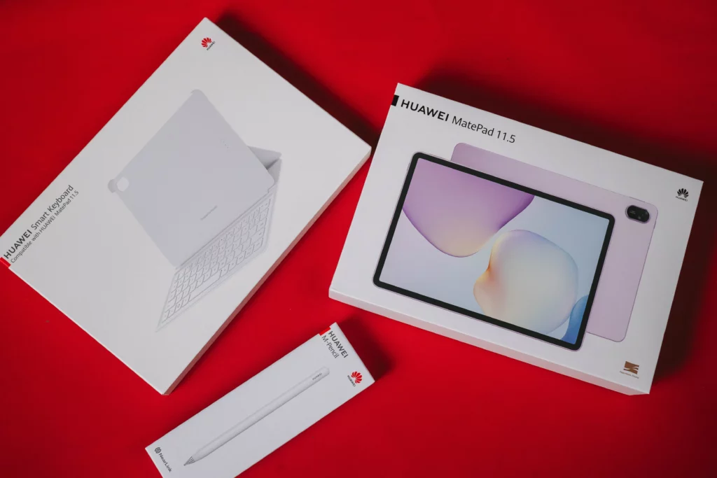 HUAWEI MatePad 11.5 unboxing with three white boxes on a red background, showing the main tablet box, the smart keyboard box, and the M-Pencil box.