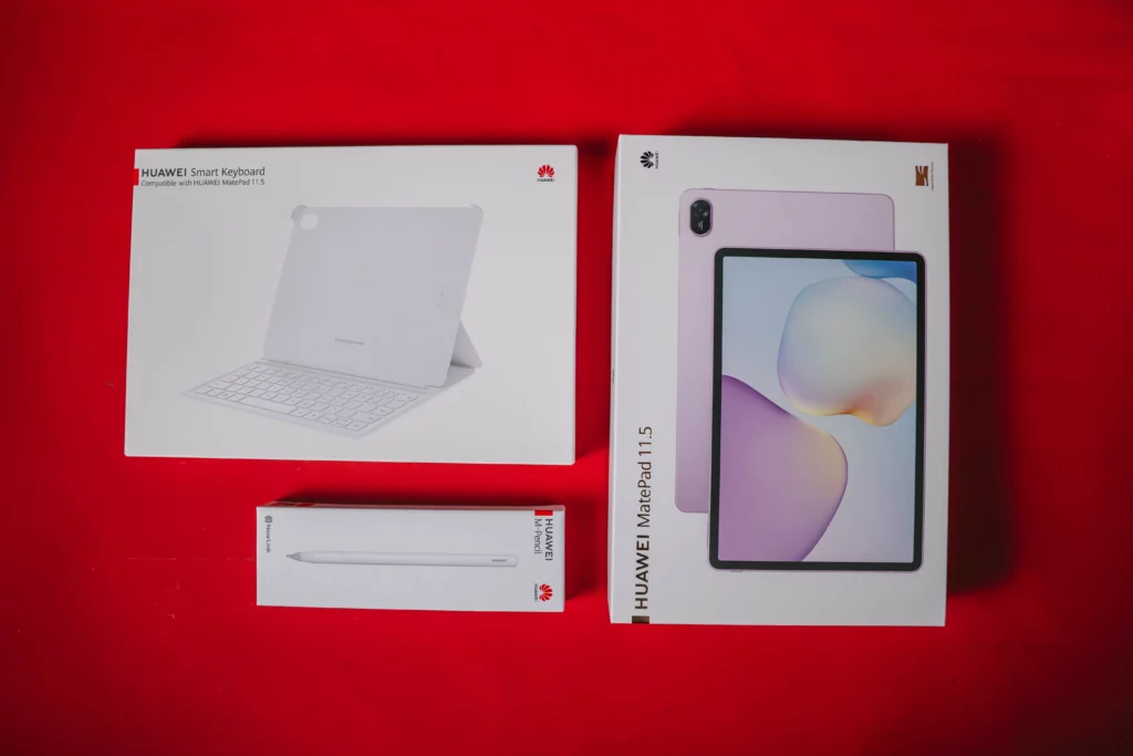 An overhead view of the three product boxes: the HUAWEI MatePad 11.5, the Smart Keyboard, and the HUAWEI M-Pencil, all arranged on a red surface.