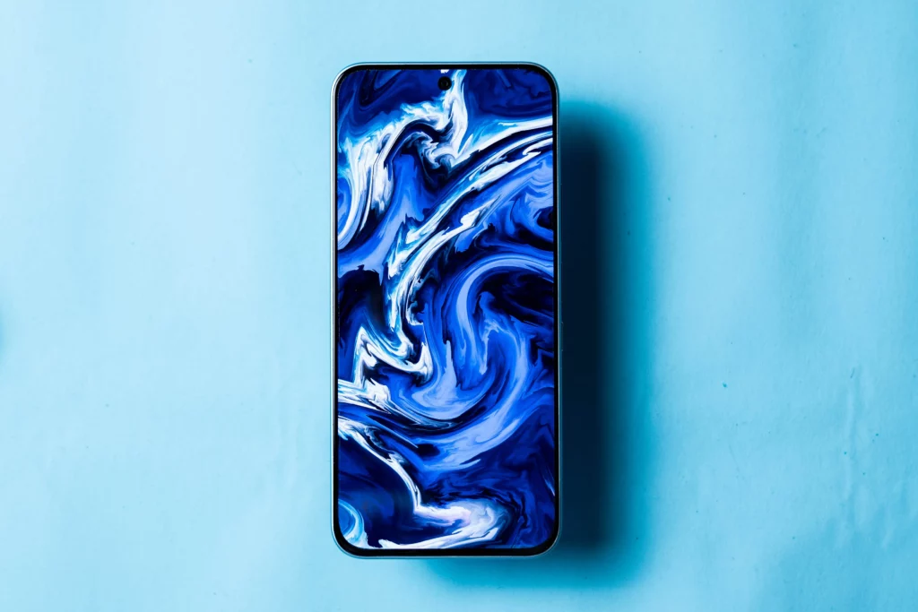 The front of the Infinix HOT 60 Pro phone with a blue and white abstract liquid art wallpaper displayed on its screen.