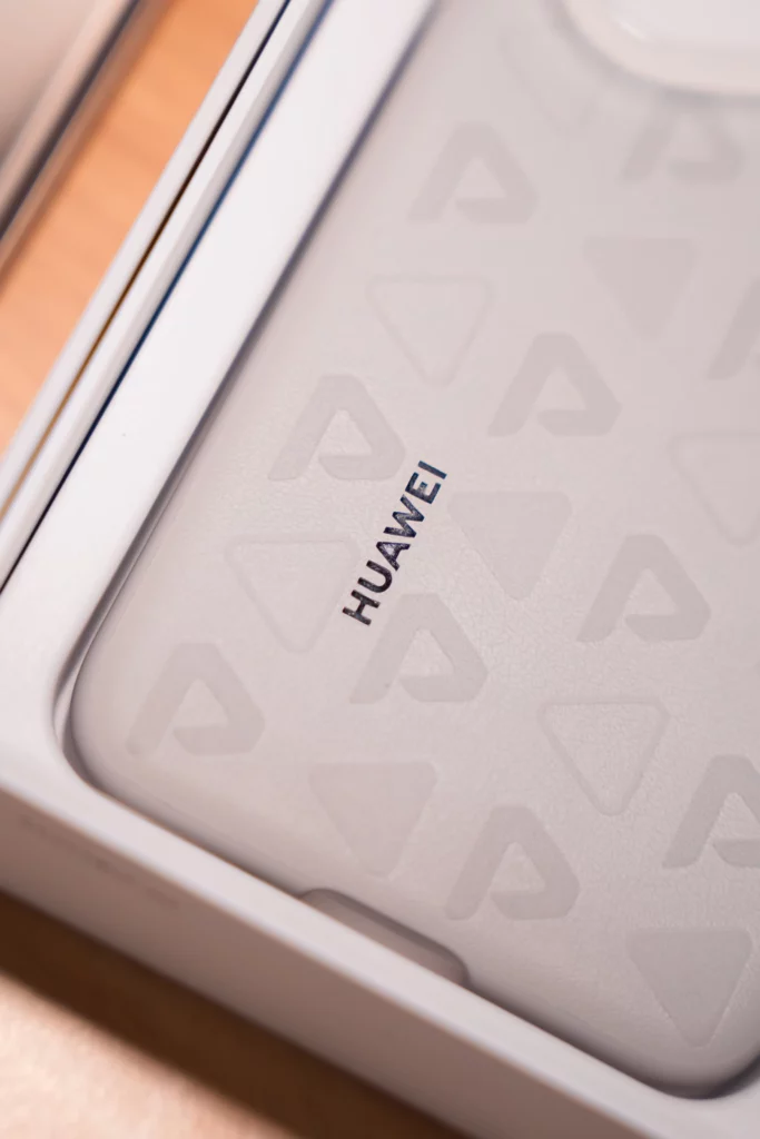 A close-up shot inside the HUAWEI Pura80 Ultra box, showing the included clear phone case with "HUAWEI" branding and a textured pattern of repeating "P" shapes.