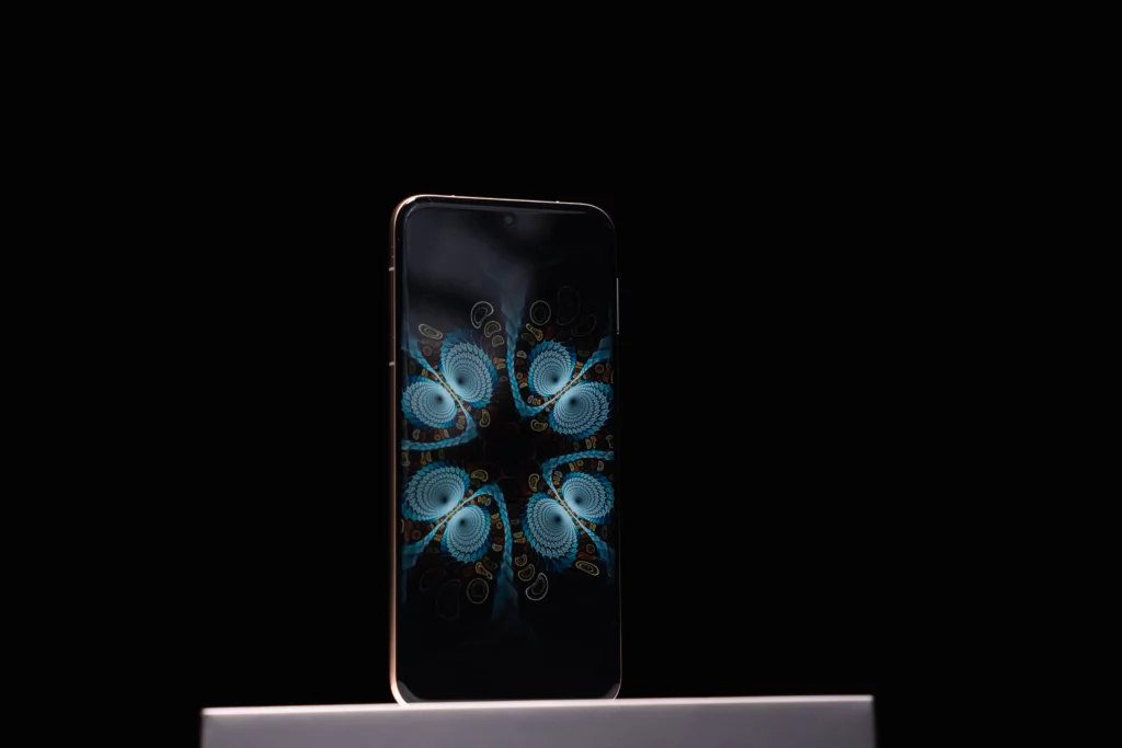 A HUAWEI Pura80 Ultra smartphone standing upright against a dark background, displaying a vibrant, symmetrical, blue and orange fractal wallpaper on its screen.