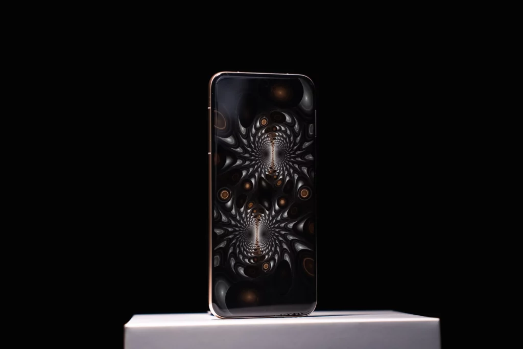 A vertical shot of a HUAWEI Pura80 Ultra smartphone standing on a white surface against a black background, displaying a complex, symmetrical abstract pattern in shades of grey and orange on its screen.