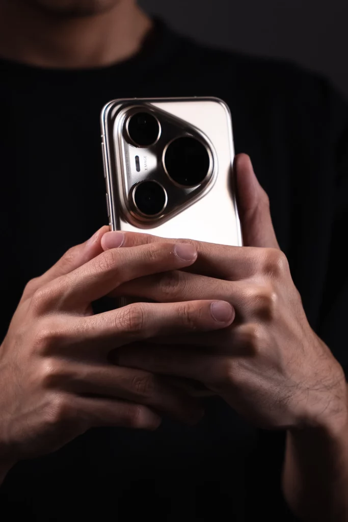 A close-up of hands holding a silver HUAWEI Pura80 Ultra smartphone, focusing on the prominent, large camera module with three lenses.