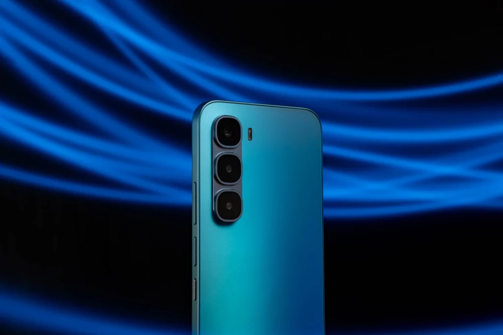 A dramatic close-up of the back of a blue smartphone against a dark background with flowing blue light trails. The phone features a vertical triple-camera module on its top left corner. The light trails create a dynamic and futuristic effect behind the device.