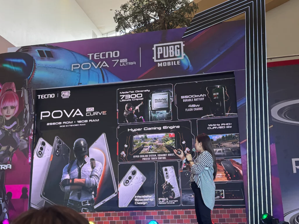 A wide shot of a stage at a product launch event. A large screen behind a woman speaking displays a promotional image for the TECNO POVA 5G Curve, detailing specs like a MediaTek Dimensity 7300 chipset, 5500mAh battery with 45W flash charge, and a 144Hz FHD+ curved screen. The event has a gaming theme with graphics for PUBG Mobile and a large TECNO logo.
