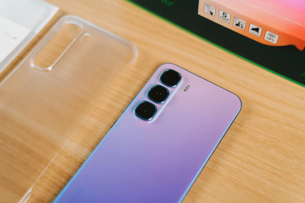 Close-up of the Infinix HOT 60 Pro+'s triple camera module and matte purple back with a clear protective case beside it.