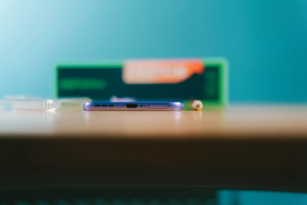 Extreme side profile view of the super-thin Infinix HOT 60 Pro+ on a wooden surface, emphasizing its slimness.