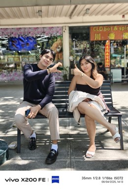 A full-shot portrait taken with the vivo X200 FE and its ZEISS co-engineered camera. A man and a woman are sitting on a bench outdoors. The EXIF data at the bottom shows the photo was taken at 35mm.