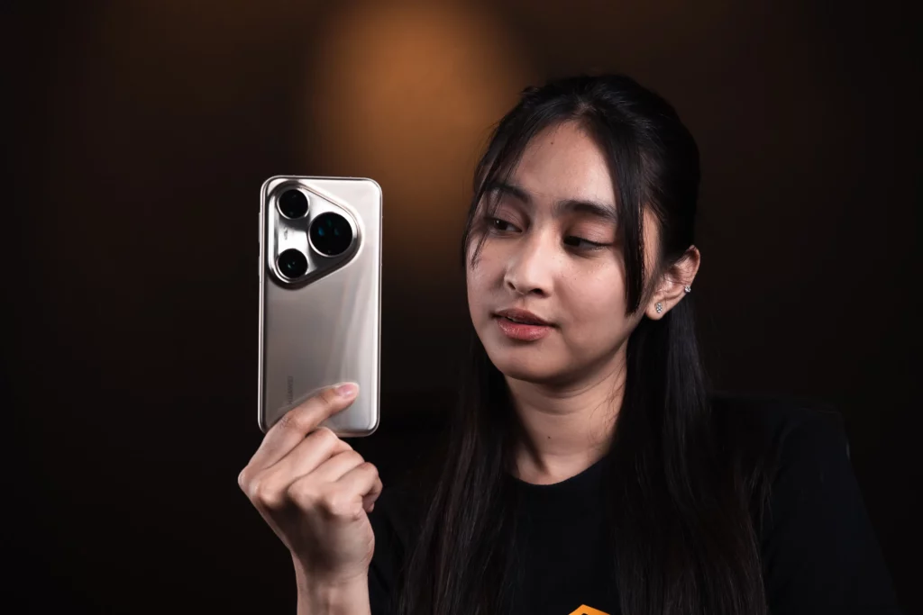 A young woman holding and looking at a HUAWEI Pura 80 series smartphone, showcasing its camera module and silver-colored back.