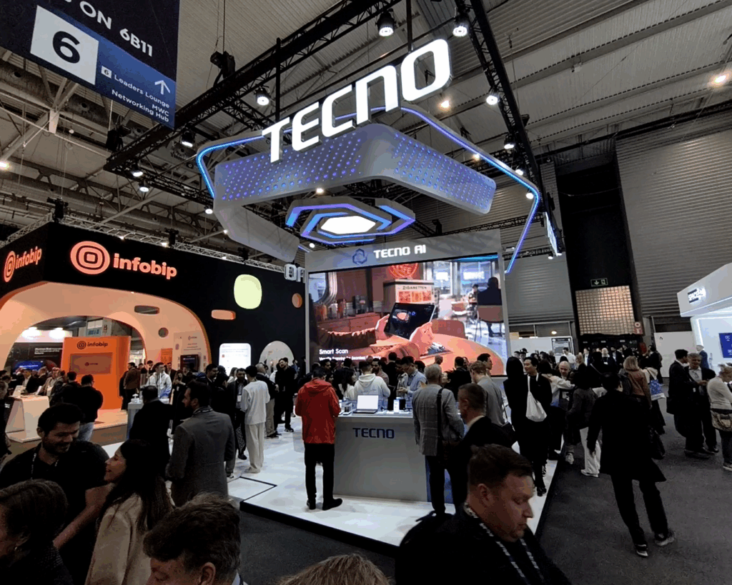 A wide shot photo of TECNO's booth in MWC 2025 in Barcelona, Spain. Showing a large display and a lot of people.