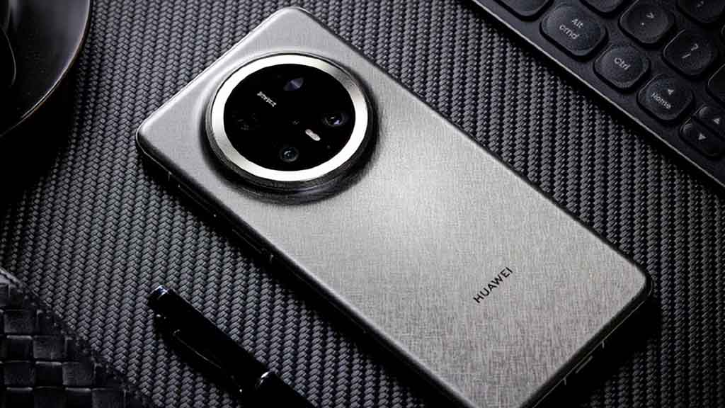 A close-up, high-angle shot of a HUAWEI smartphone with a brushed silver metallic back and a large, circular camera module. The phone is placed on a dark, textured surface next to a pen and the corner of a keyboard.