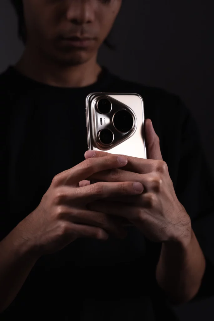 A person holding the HUAWEI Pura 80 Ultra to their face, showcasing the phone's sleek profile and the unique design of its camera module.