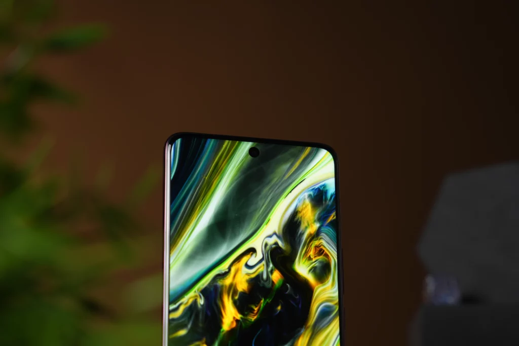 A close-up shot of the Vivo V60's screen, showing the top of the display with a punch-hole camera and a dynamic, fluid wallpaper in green, yellow, and blue hues.