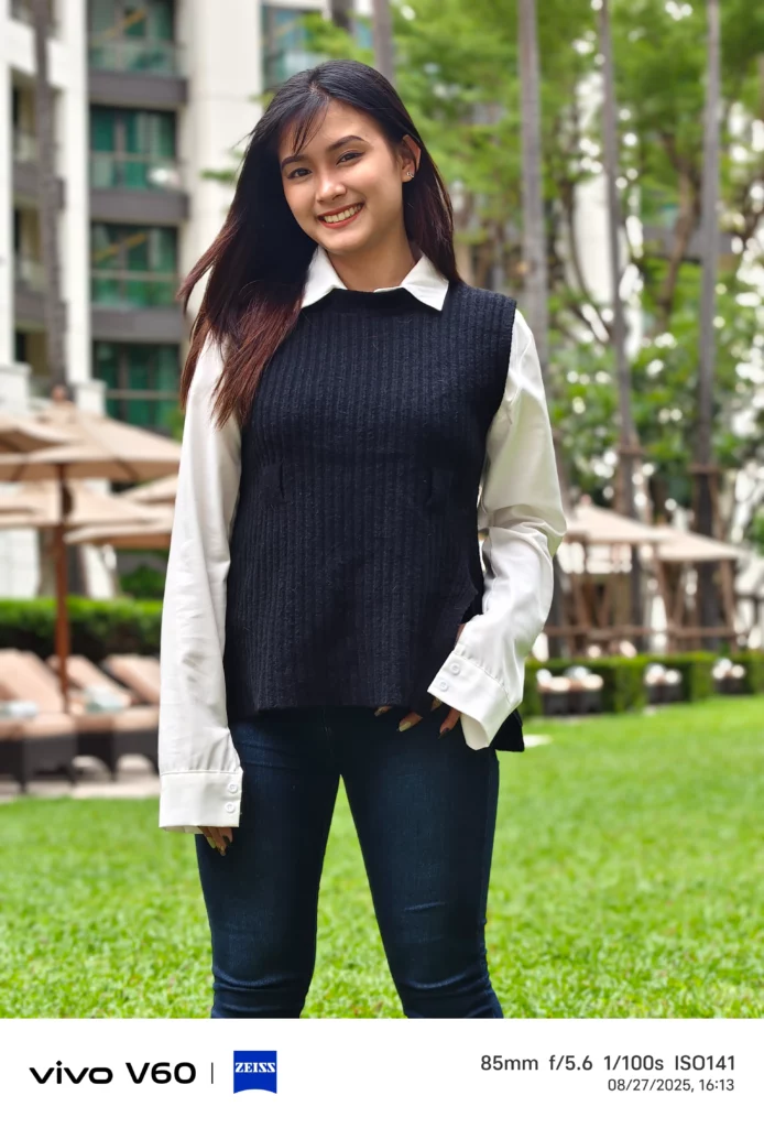 A portrait shot taken with the Vivo V60's 85mm lens, featuring a smiling woman with a blurred outdoor background. Photo data is visible at the bottom.