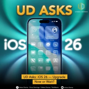 An image posing a question about iOS 26. A smartphone, likely an iPhone, is centered in the frame, displaying its home screen with a new layout. The screen features redesigned widgets for weather and contacts, and the app icons appear to be in a grid with rounded corners. The words "UD ASKS" are at the top, and "iOS 26" is written in large, bold letters on either side of the phone. A yellow banner at the bottom asks, "UD Asks: iOS 26 — Upgrade Now or Wait?"