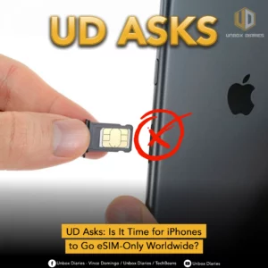 A person’s hand removes a SIM card tray from an iPhone, with a red “X” drawn over the SIM card, symbolizing its removal. The text “UD Asks” appears at the top in bold gold letters, and a caption at the bottom reads: “UD Asks: Is It Time for iPhones to Go eSIM-Only Worldwide?” The Unbox Diaries logo is visible in the top-right corner.