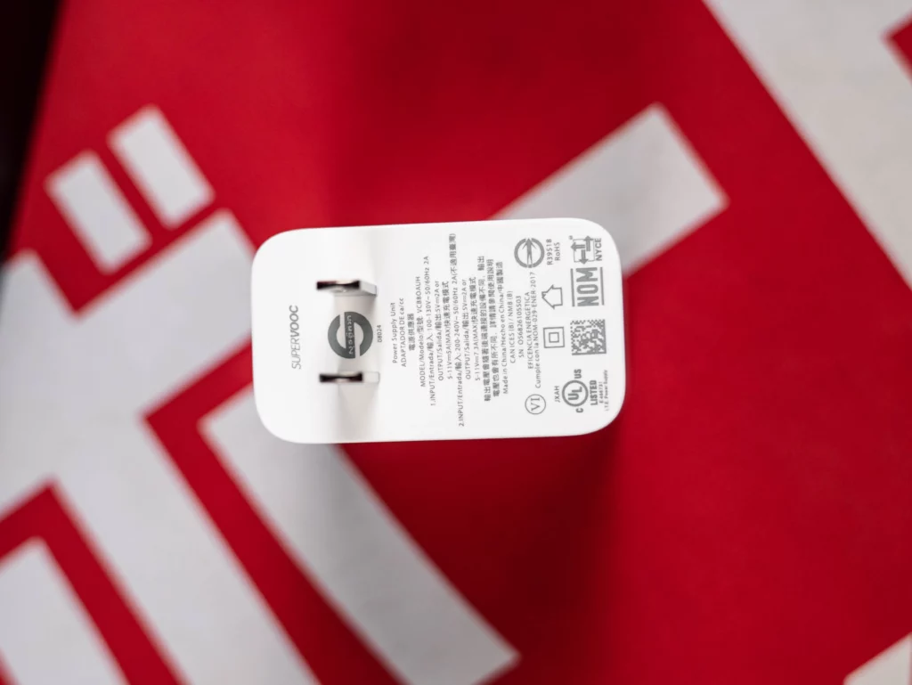 An overhead shot of the realme SuperVOOC fast charger on a red background. The image clearly shows the branding and technical specifications of the power adapter.