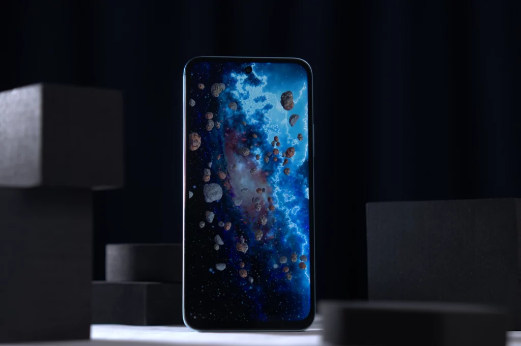 The screen of a light blue POCO smartphone displays a vibrant space-themed wallpaper with asteroids and a nebula.