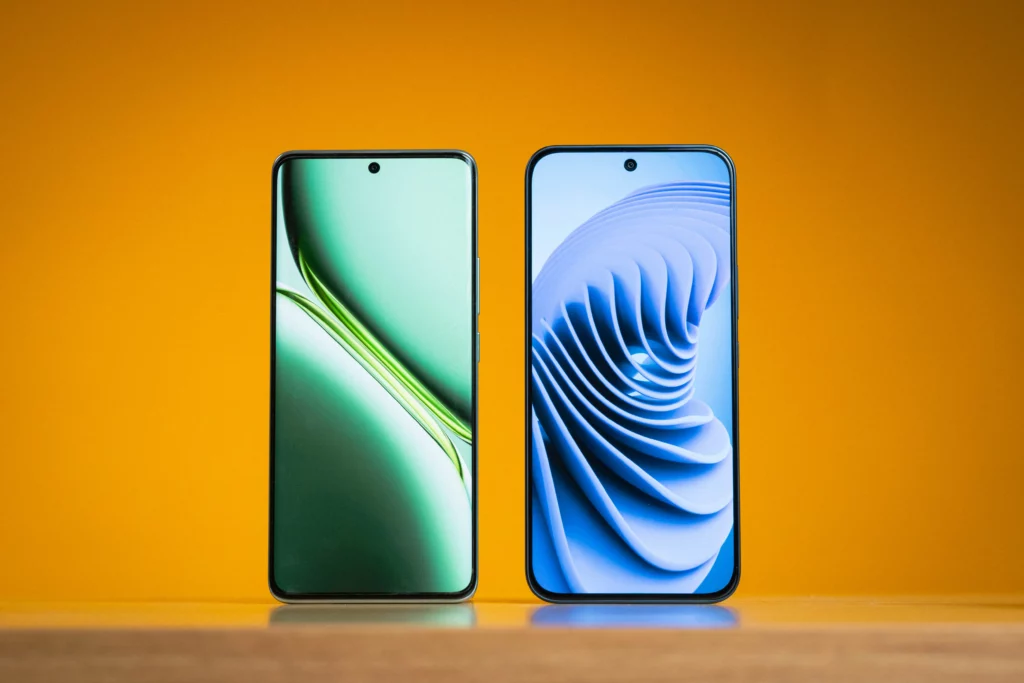 Two smartphones standing upright side-by-side against an orange background. The phone on the left displays a green, abstract wallpaper, and the phone on the right displays a blue, curved, wave-like wallpaper. Both have a hole-punch front camera cutout.