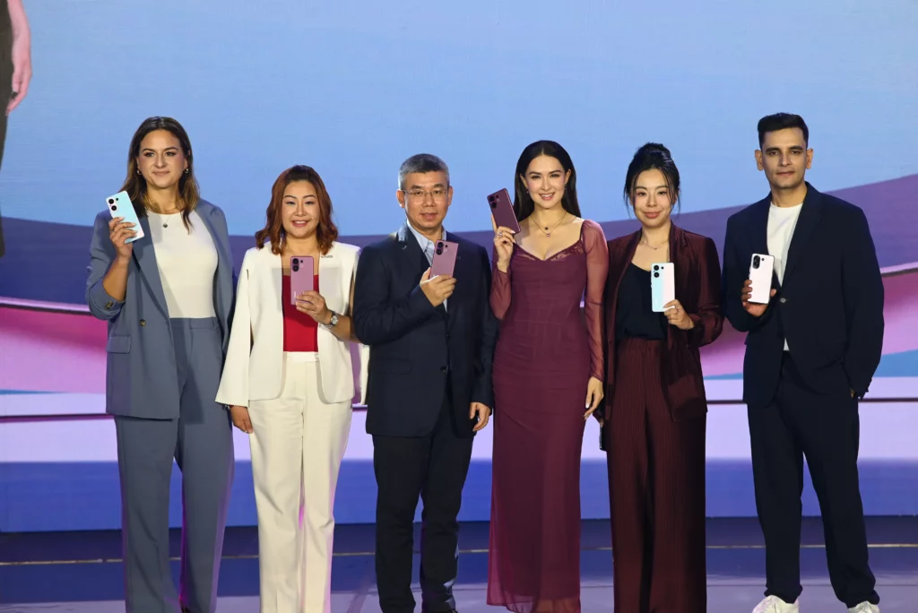 A group of six people stand on a stage, holding vivo V60 phones in various colors. From left to right: Franziska Hoffmann, Hazel Bascon, Kenny Zeng, Marian Rivera, Lulu Liu, and Keshav Chugh. They are all smiling and posing for the camera at the vivo V60 launch event.