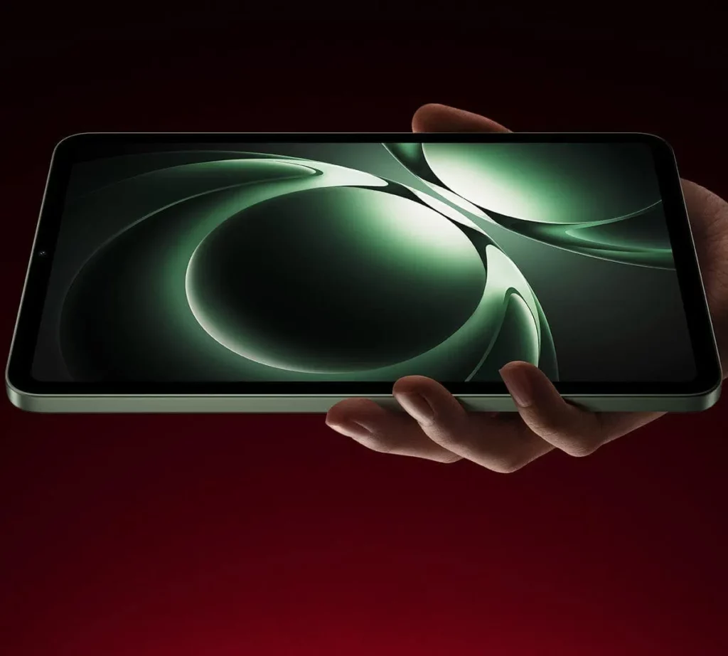 A hand holding the new Redmi K Pad tablet, displaying a swirling green graphic on its screen, with a dark red background.