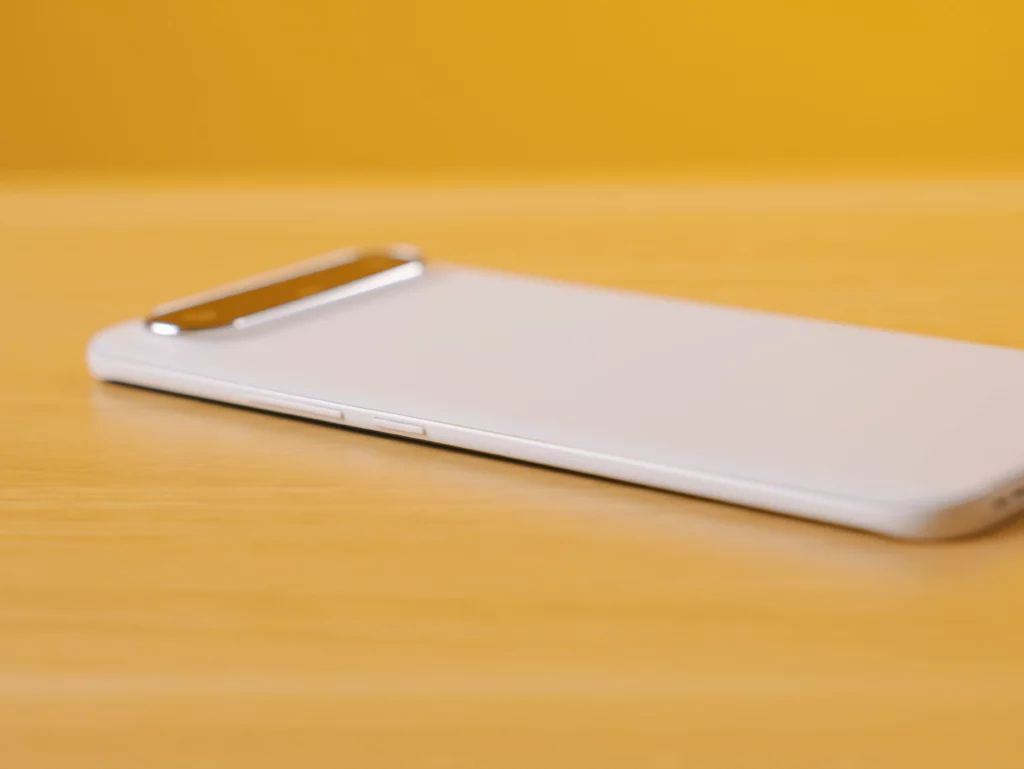 Side view of the white TECNO SPARK Slim phone lying on a wooden surface, showing the power and volume buttons on the right side.