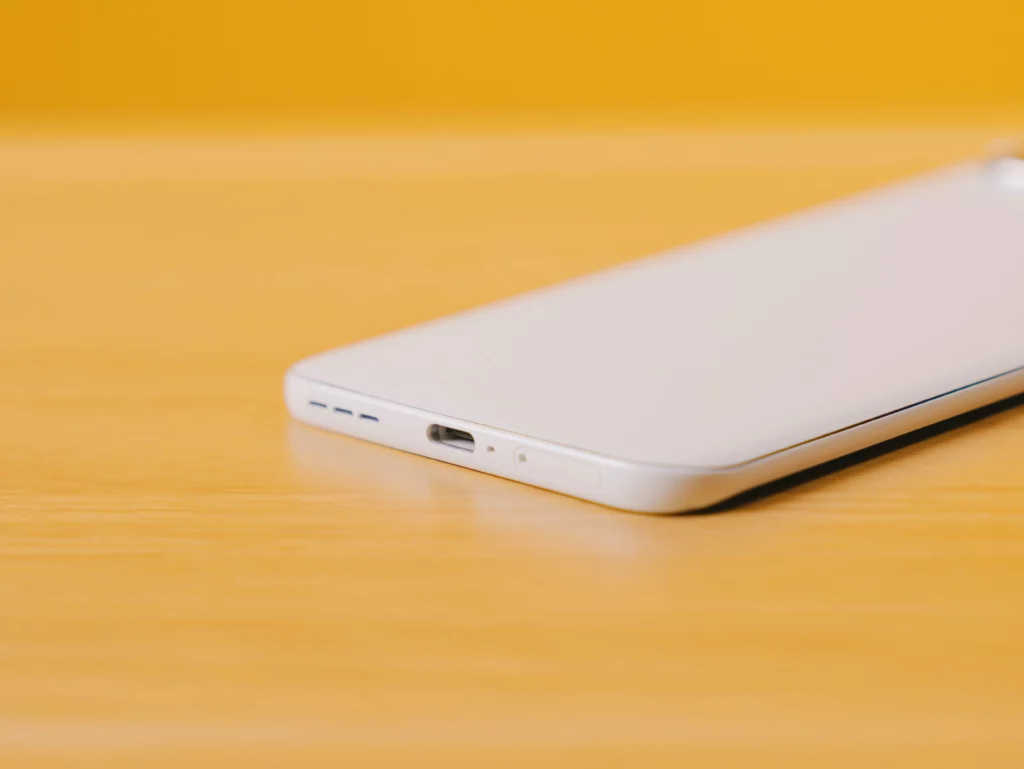 Close-up of the bottom edge of the white TECNO SPARK Slim phone, showing the USB-C charging port, speaker grille, and microphone.