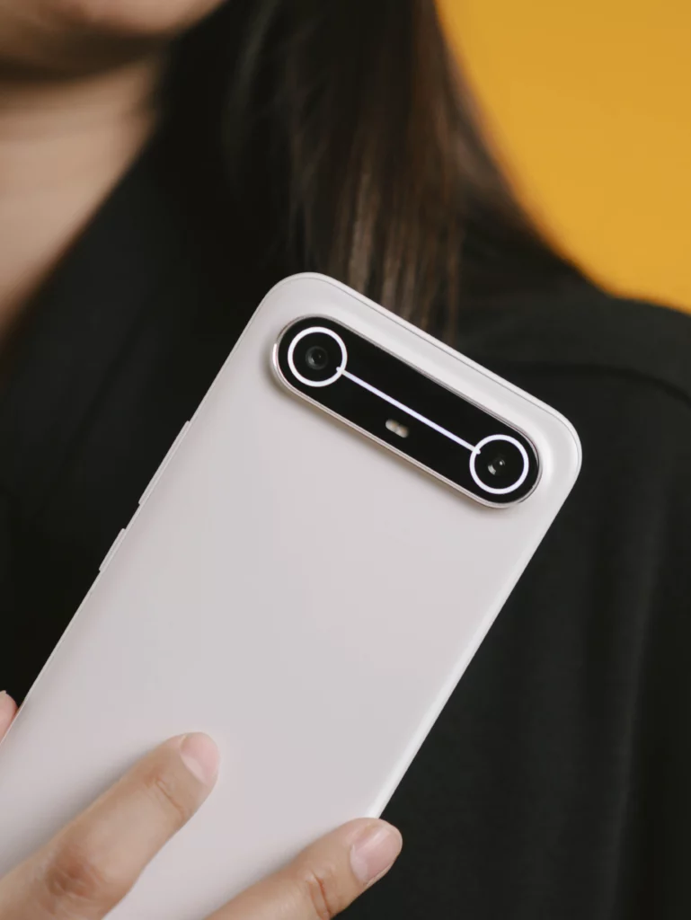 Close-up of the white TECNO SPARK Slim held in a person's hand, highlighting the large, sleek, dual-ring camera system on the back.