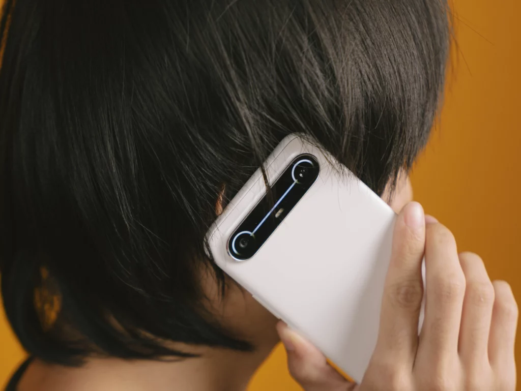 Person holding the TECNO SPARK Slim phone to their ear, making a call, showcasing the back camera design during use.