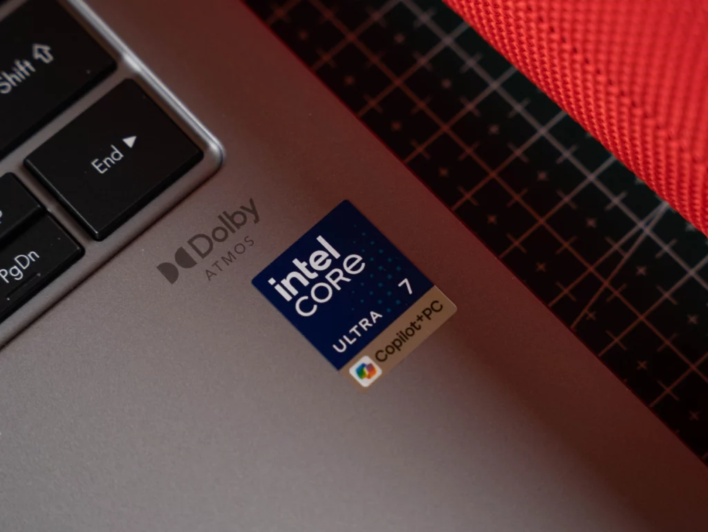 An extreme close-up of a sticker on the laptop's palm rest next to the keyboard. The sticker reads "intel Core ULTRA 7 Copilot+ PC" and the "Dolby ATMOS" logo is also visible.