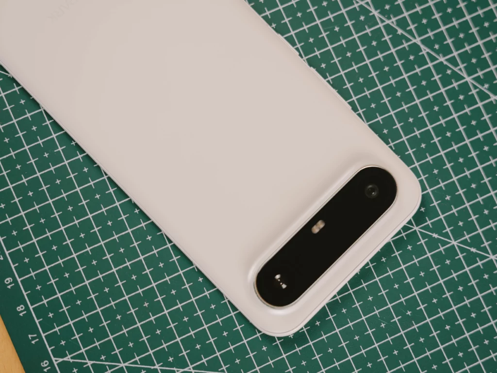 High-angle shot of the white back of the TECNO SPARK Slim phone and its black camera module, resting on a green cutting mat.