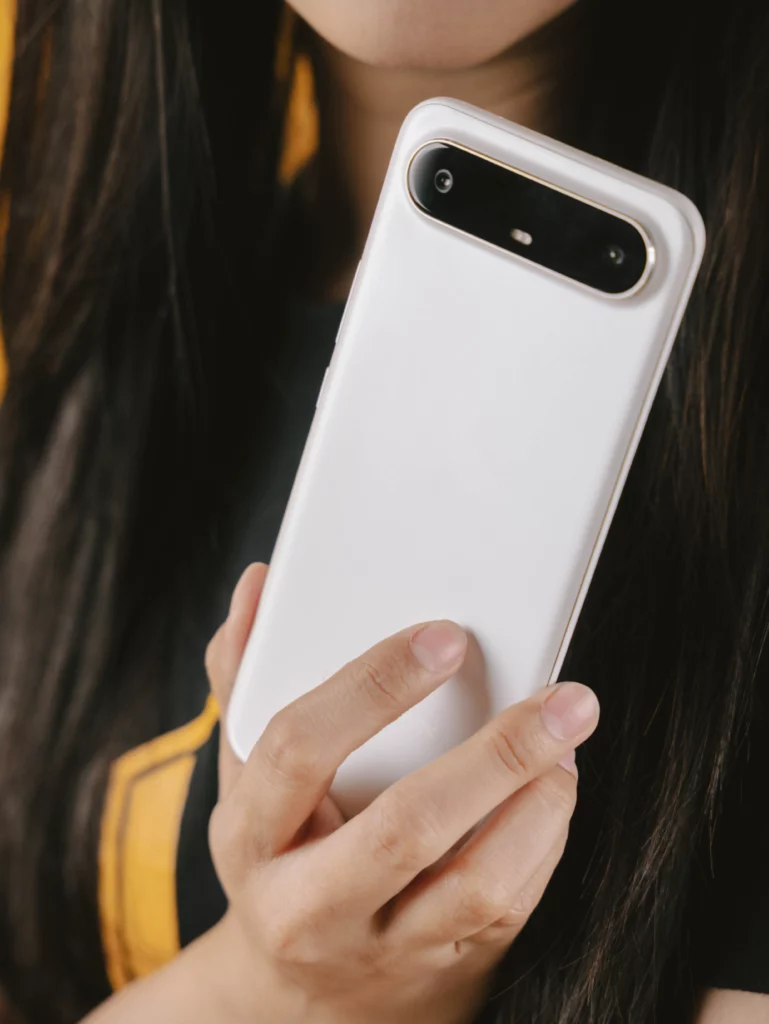 Close-up of hands holding the back of the white TECNO SPARK Slim smartphone, showing the distinctive pill-shaped black camera module.