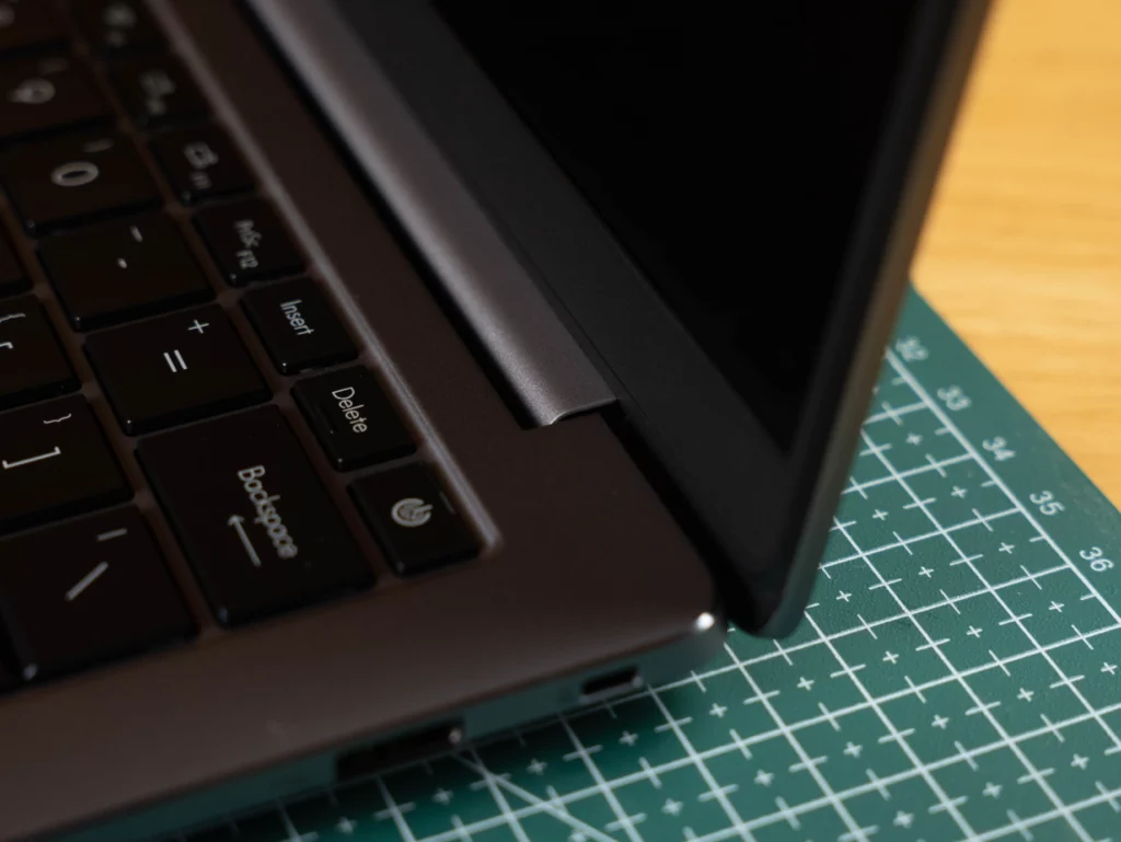 A close-up of the right corner of the laptop's keyboard and hinge area. The power button and a small section of the hinge are visible, with the screen slightly ajar.