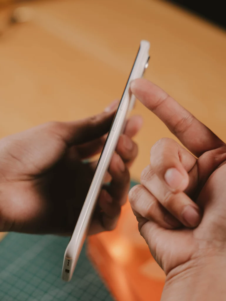 Close-up of hands holding the TECNO SPARK Slim side profile, with a finger touching the volume or power button, showing the phone's thinness.