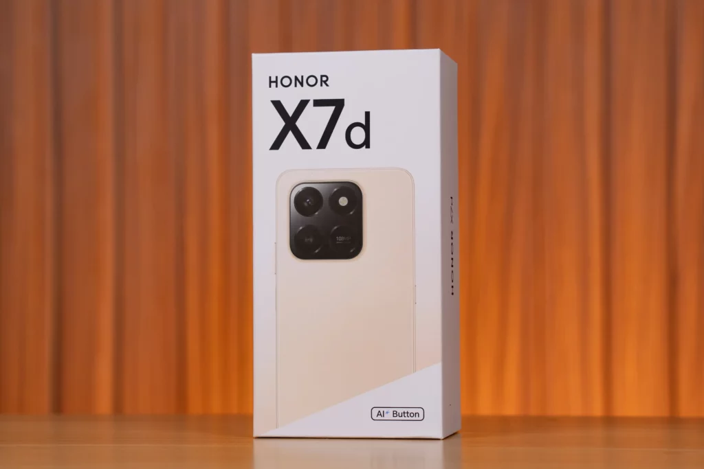 Close-up of the front of the white HONOR X7d smartphone box. The phone image on the box is a light peach/gold color with a prominent circular black camera module that shows a 108MP inscription.