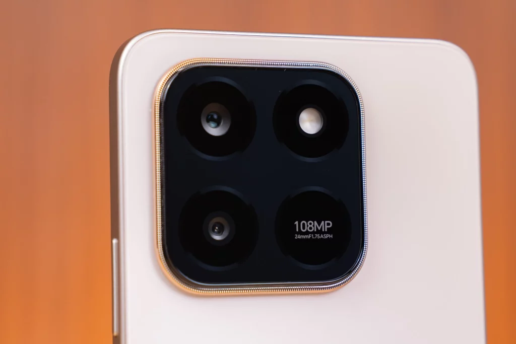 Extreme close-up of the triple-camera module on the back of the light-colored HONOR X7d phone. The black, circular module features three lenses, a flash, and a clear label indicating "108MP 24mm f/1.75 ASPH."
