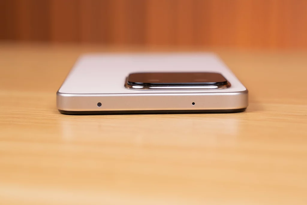 Top edge view of the HONOR X7d smartphone showing two small microphone holes. The phone's main camera module is visible in the background.