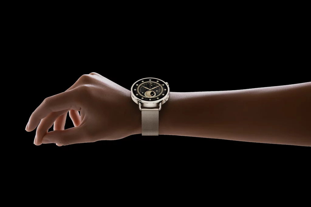 A close-up shot of a wrist wearing the Xiaomi Watch S4 (41mm) with a gold mesh band. The watch face is black with gold-tone accents and a crescent moon phase display. The background is solid black.