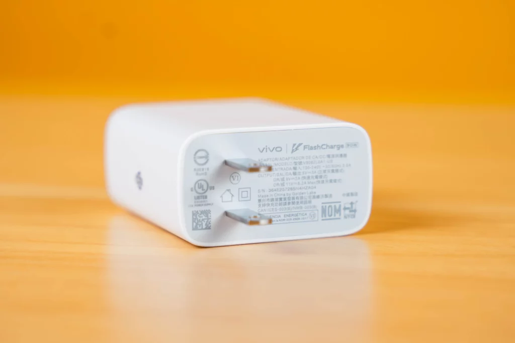 A close-up shot of the white vivo FlashCharge 80W wall adapter. The text on the adapter lists its power specifications and certifications, including its 80W capability.