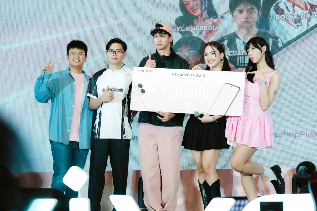 Team Kurimeow, the tournament champions, pose on stage holding an oversized check for Php 30,000, with an image of the vivo V60 Lite behind them. The team members include streamers and cosplayers.