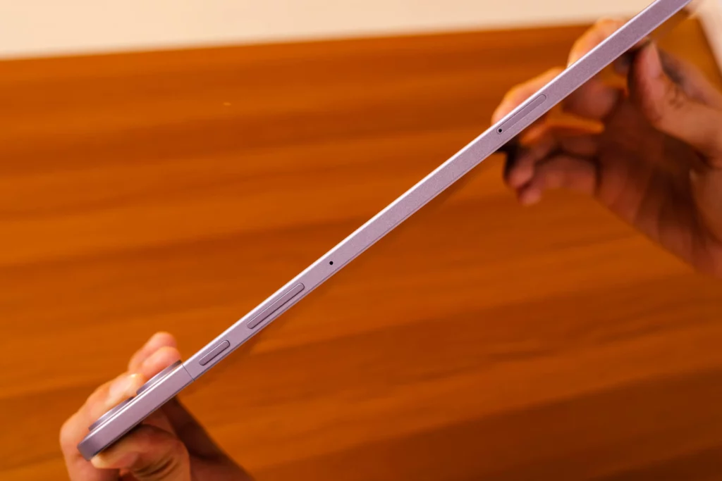 A close-up of the side profile of the Infinix XPAD 20 Pro tablet being held, showing the power button, volume rockerr, a small microphone hole, and what appears to be a SIM/microSD card tray slot.